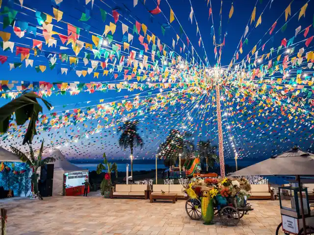 Festa junina no clube, com bandeirinhas coloridas e a represa ao fundo.