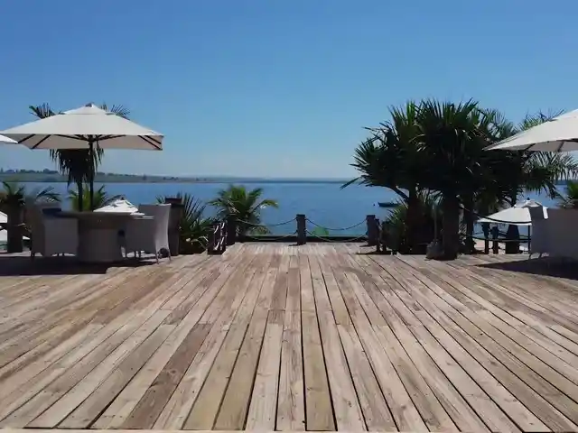 Deck de madeira com ombrelones, de frente para a represa.